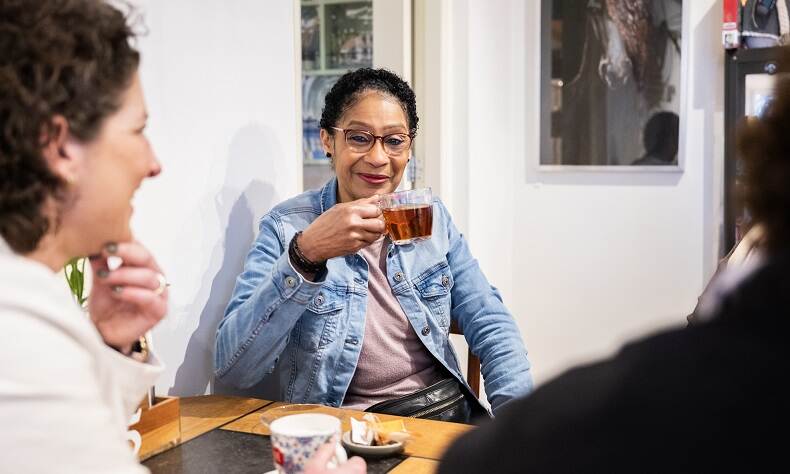 Een vrouw drinkt thee in gezelschap