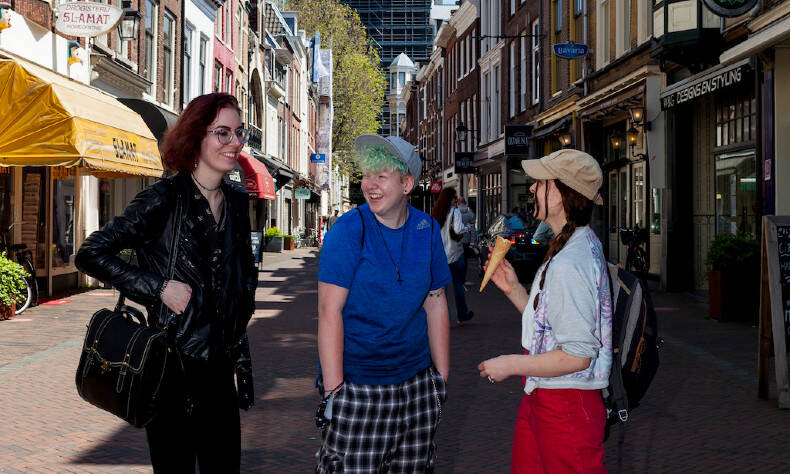 Drie jonge mensen praten met elkaar op straat met de Dom op de achtergrond