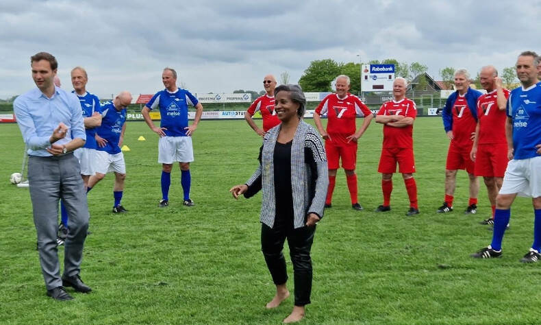 Een aantal mensen voetballen samen met de OldStars op een voetbalveld